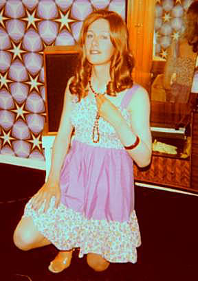 Joy crouches holding red beads in front of mirror