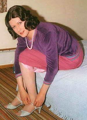 Joy sits on the bed doing up her grey sandals